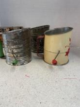 Vintage flour sifters, various cookie cutters, tin cups, mason jars, eating utensils